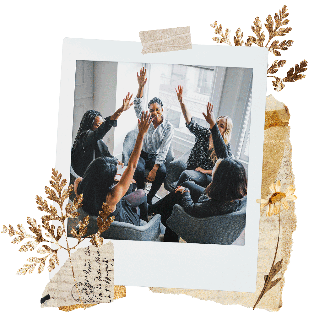 A group of people holding their hands up in the air, while sitting in chairs. This image is inside of a polaroid frame with illustrated tape and flowers surrounding the frame.